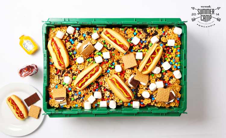 A green MakeSpace storage bin full of hot dogs, s'mores, M&Ms, pretzels, marshmallows, chocolate, and more.