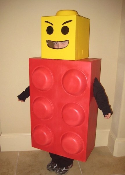 A boy is wearing a red and yellow LEGO man Hallween costume.