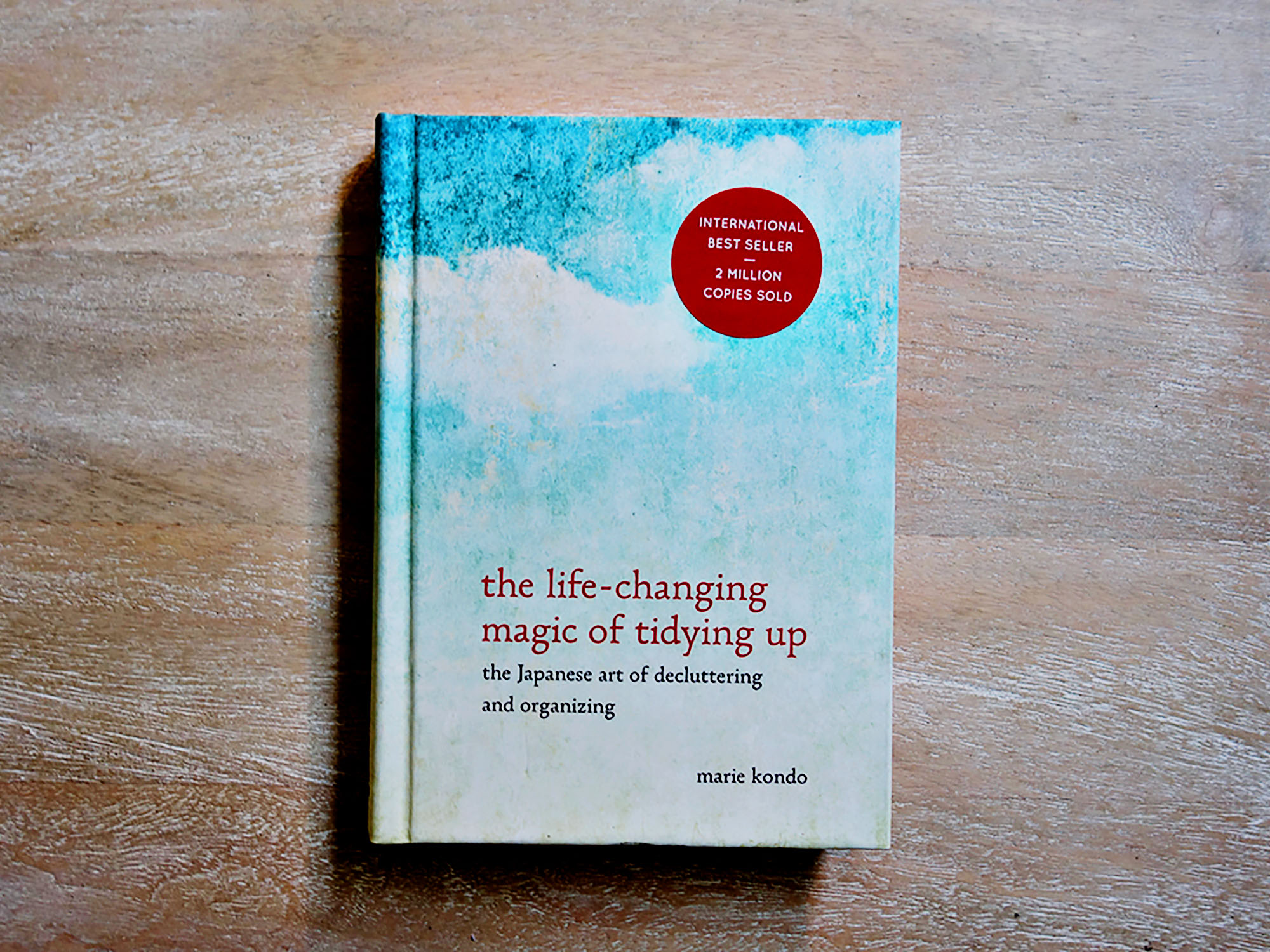 Marie Kondo The Life-Changing Magic of Tidying Up book on a wooden surface.