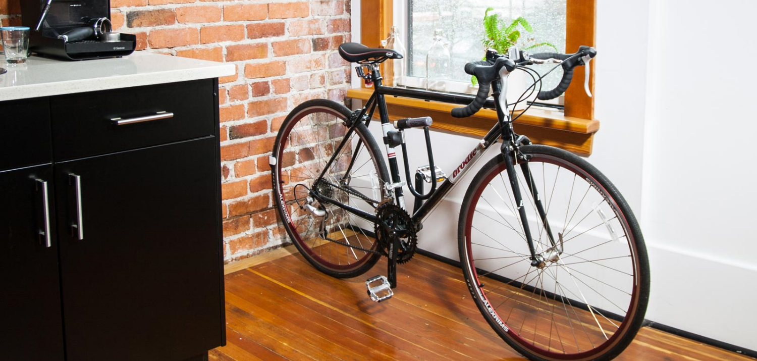 CLUG bike storage rack is storing a black bike inside a tiny kitchen.