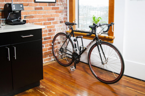 CLUG bike storage rack is storing a black bike inside a tiny kitchen.