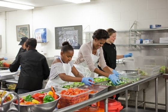 MicroGreens founder Alli Sosna removes ingredients from food storage containers to make salads with Michelle Obama at DC Central Kitchen in Washington DC.