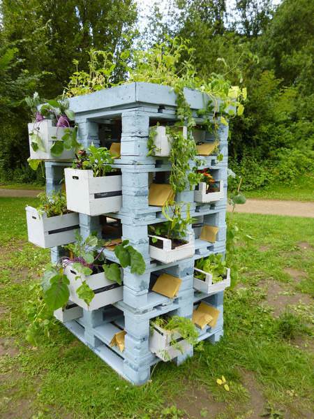 A DIY planter tower made from reclaimed wood pallets with plant storage.