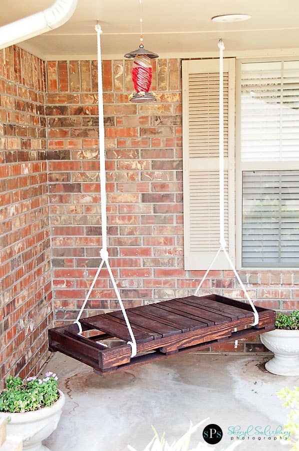A DIY wooden shipping pallet swing on a porch.