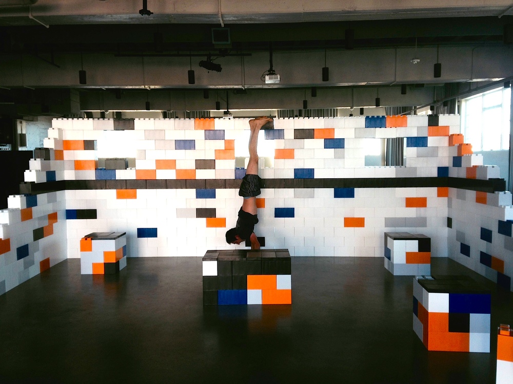 A man doing a handstand in a homa yoga studio made of big LEGO-resembling EverBlocks.