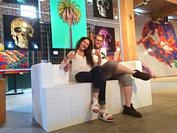 A woman and man sitting on a white sofa made of EverBlocks, which look like big LEGOs.