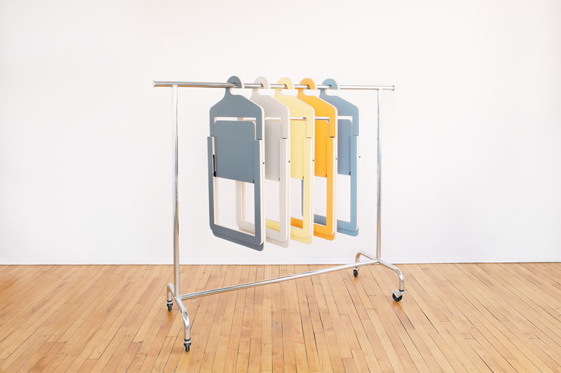 Black, grey, yellow, coral, and marine Umbra Shift Hanger Chairs are hanging on a rolling clothes rack.