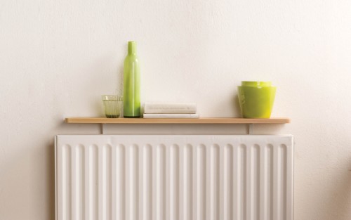 A drinking glass, decorative vase, books, and pots are stored on top of a radiator shelf kit from B!Organised.