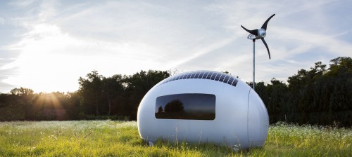 The Ecocapsule, a self-sufficient pod/tiny house on wheels that's available for pre-order, is outside in the grass during the daytime.