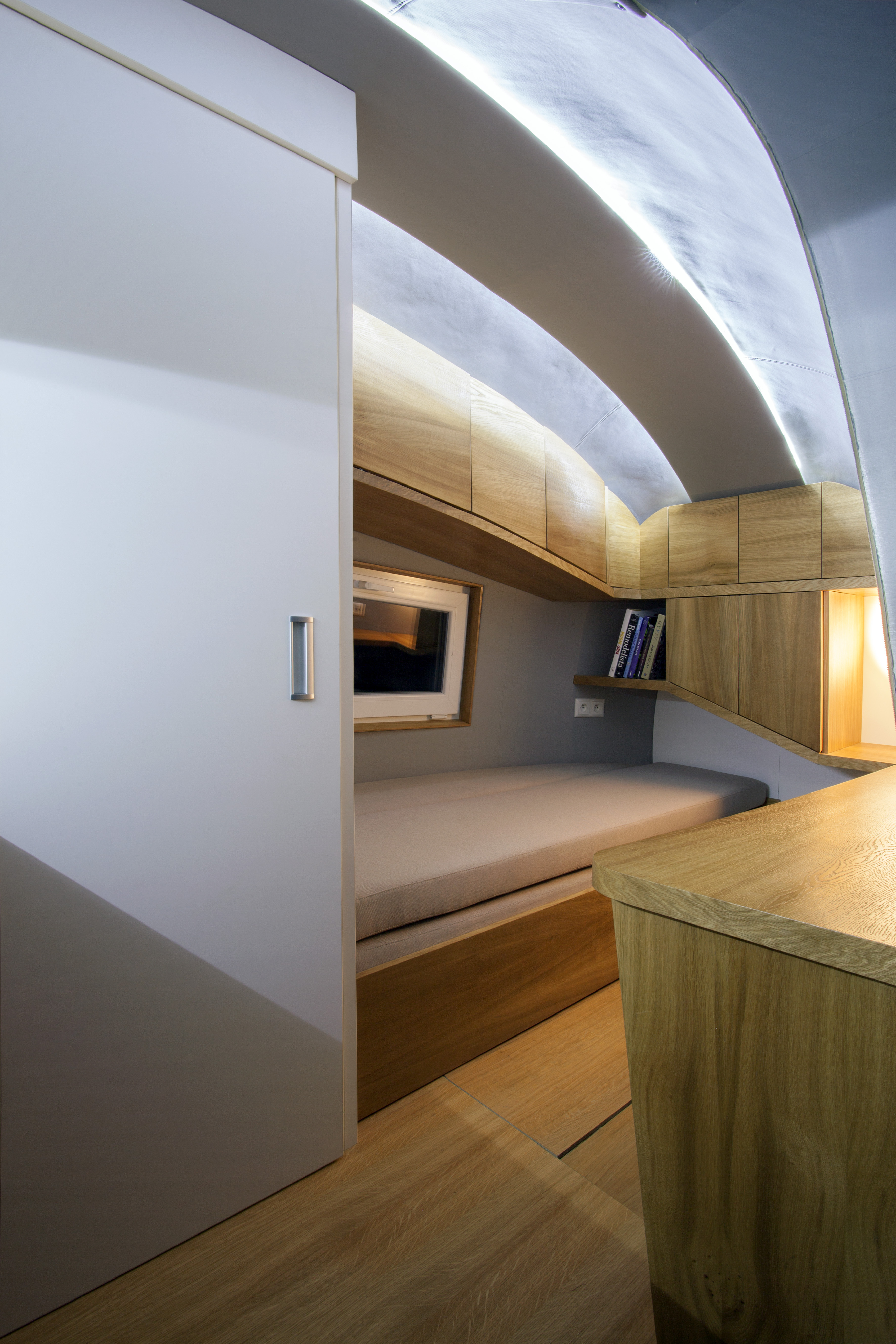 The Ecocapsule's multipurpose living area has a folding bed, storage cabinets, and a desk.