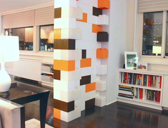 The interior of a small apartment with a room divider/accent wall made of EverBlocks that resemble giant LEGOs.