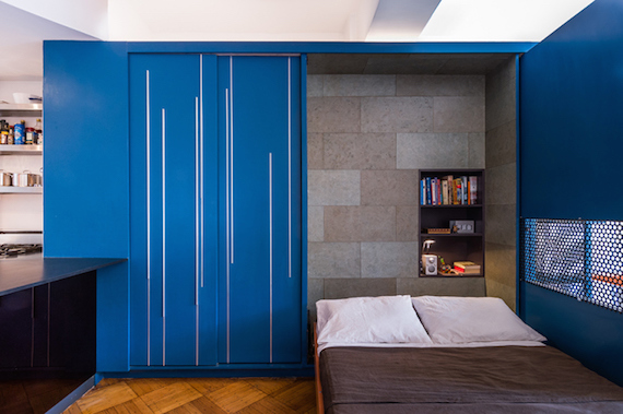 The bedroom, murphy bed, mattress, pillows, bookshelf, and closet inside of Unfolding Apartment's blue storage cabinet/transforming furniture.