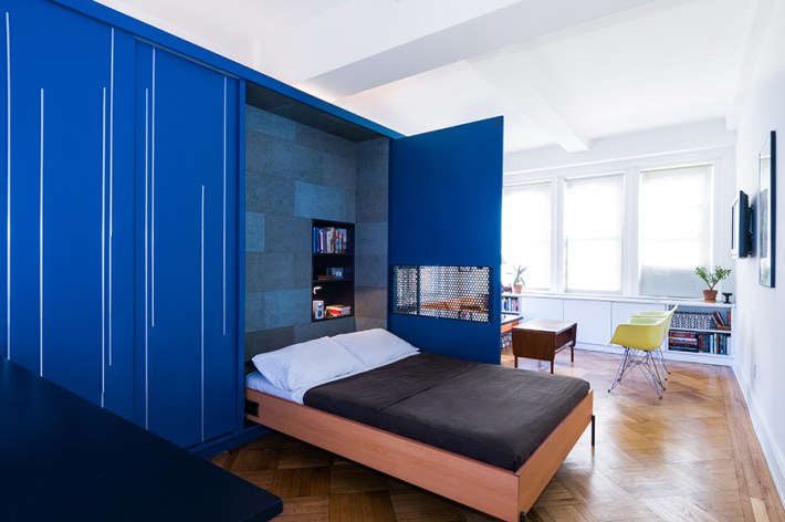 The interior of the Unfolding Apartment in Manhattan, New York has a blue convenient self-storage unit with a murphy bed, home bar, closet, and more.