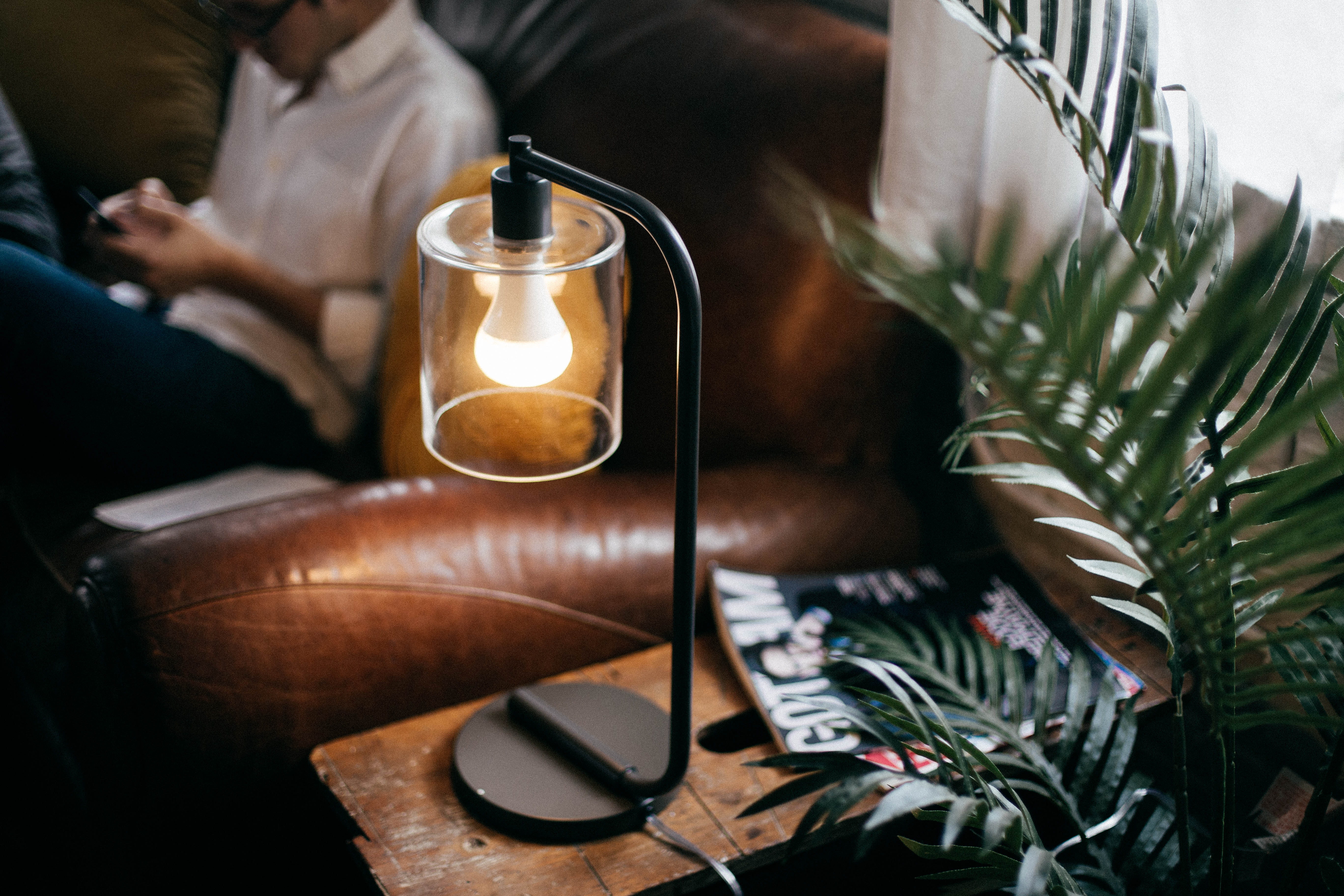 A space-saving Twist Smart LED Lightbulb, which is also an AirPlay speaker, is installed in a tiny black lamp and glowing.