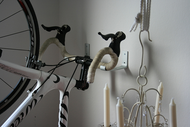 A bike rack made of two white IKEA KVARTALs is storing a bicycle vertically.
