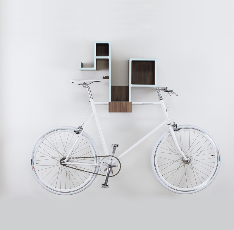A veneer Tamasine Osher Pedal Pod is mounted to a light gray wall and storing a white classic bicycle.