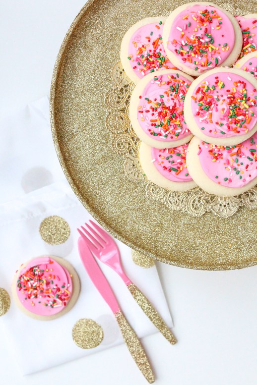 A do-it-yourself gold-glittered cake stand gold-glittered pink fork and knife are fancy DIY decorations for a fancy NYE party.