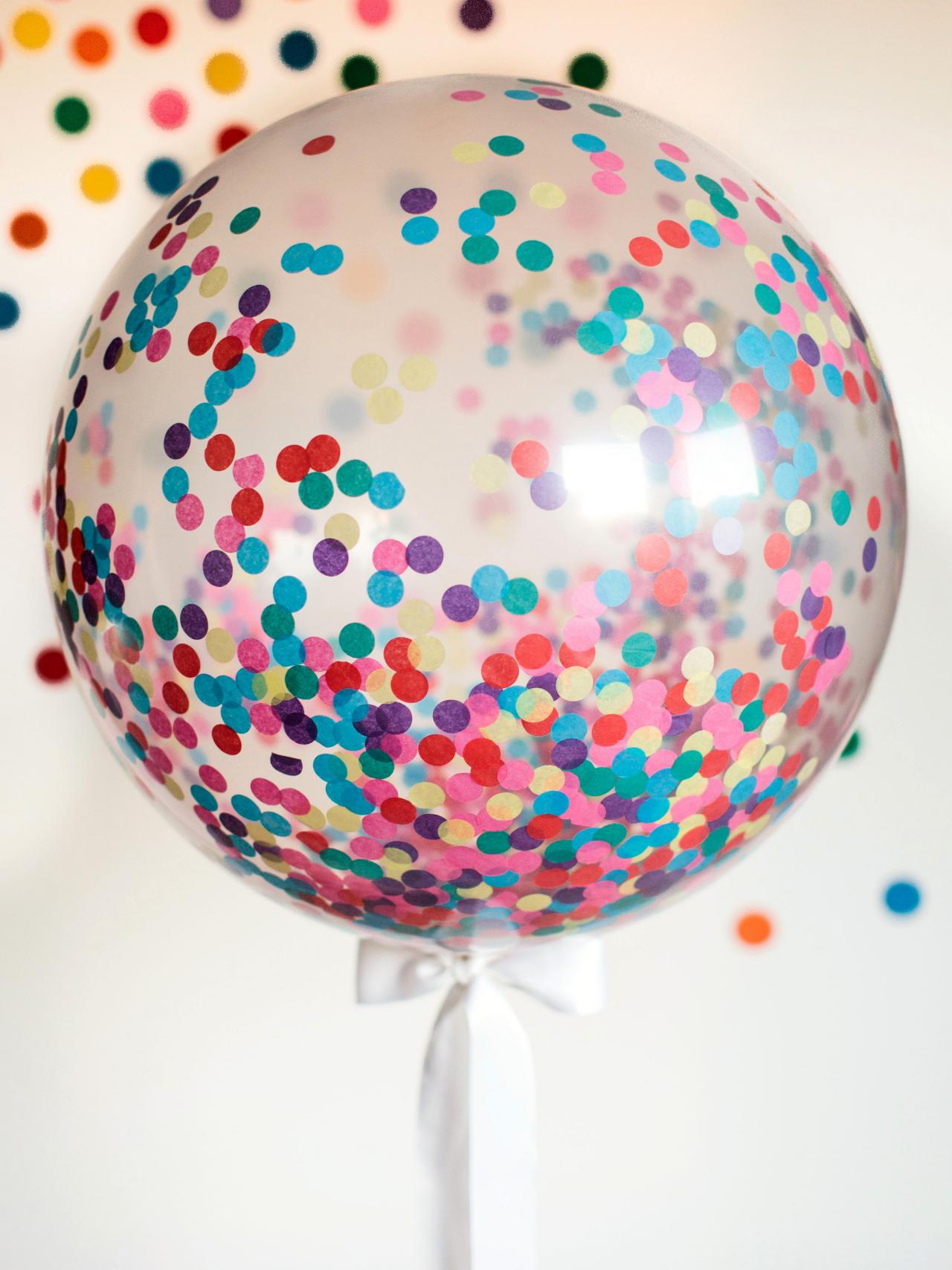 A big transparent DIY confetti balloon with a white ribbon tied to it.