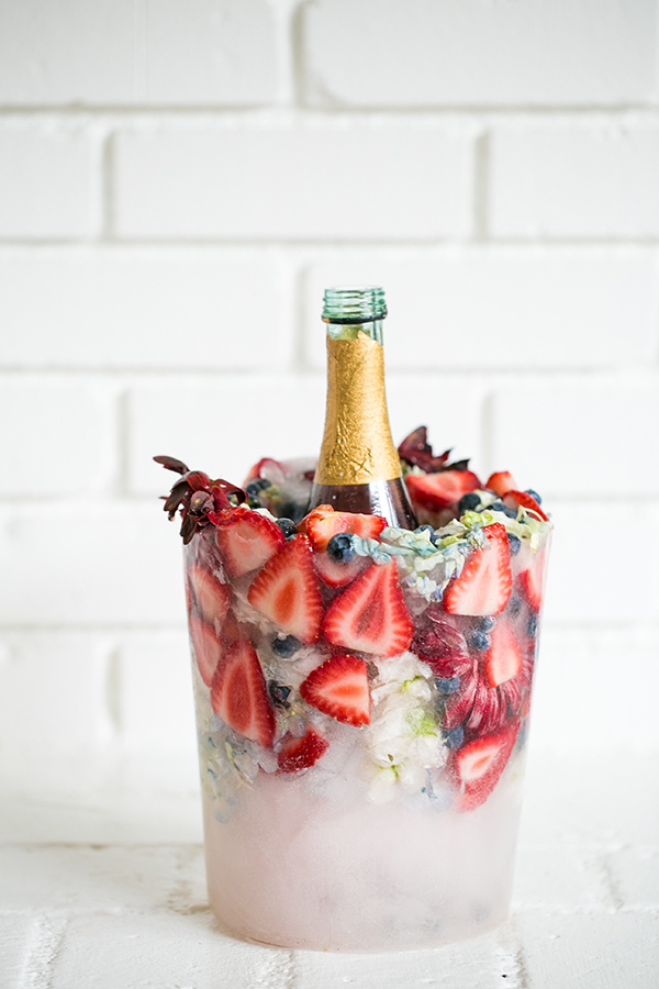 A DIY ice bucket made from ice, strawberries, blueberries, and flowers.