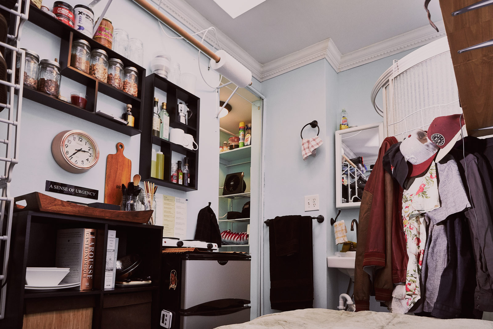 The left side of Grayson Altenberg's 100-square-foot micro-apartment has a bookcase, an organizing tray, and wall-mounted storage shelves.