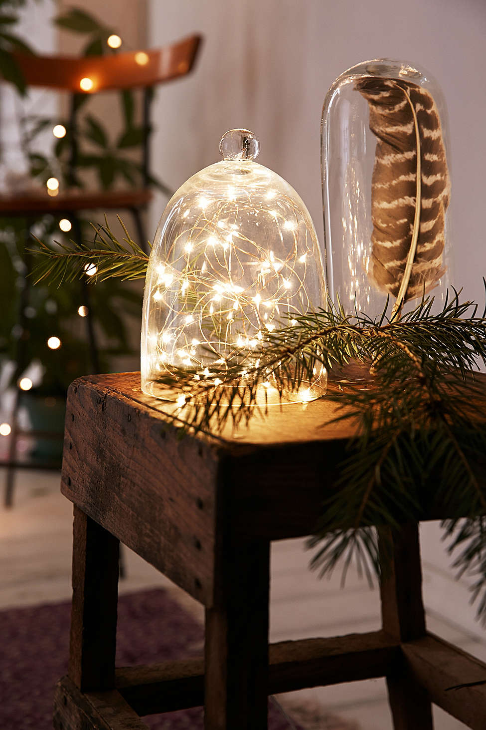 A terrarium is storing glowing holiday decoration string lights on a wooden table in a small apartment.