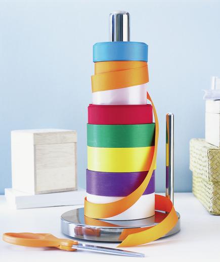 8 spools of colored ribbon stored on a paper towel stand is a cool holiday storage hack.