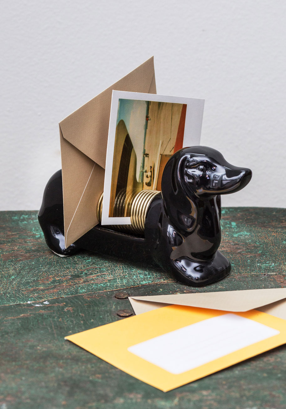 A dachshund letter organizer is on a desk and storing lan envelope and photograph.