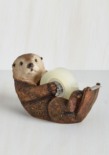 An otter tape dispenser is laying on a desk.