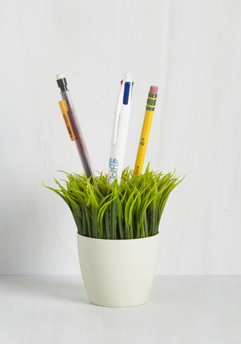 An Ideas in Bloom Desk Organizer from ModCloth that looks like grass storing pencils and a pen.