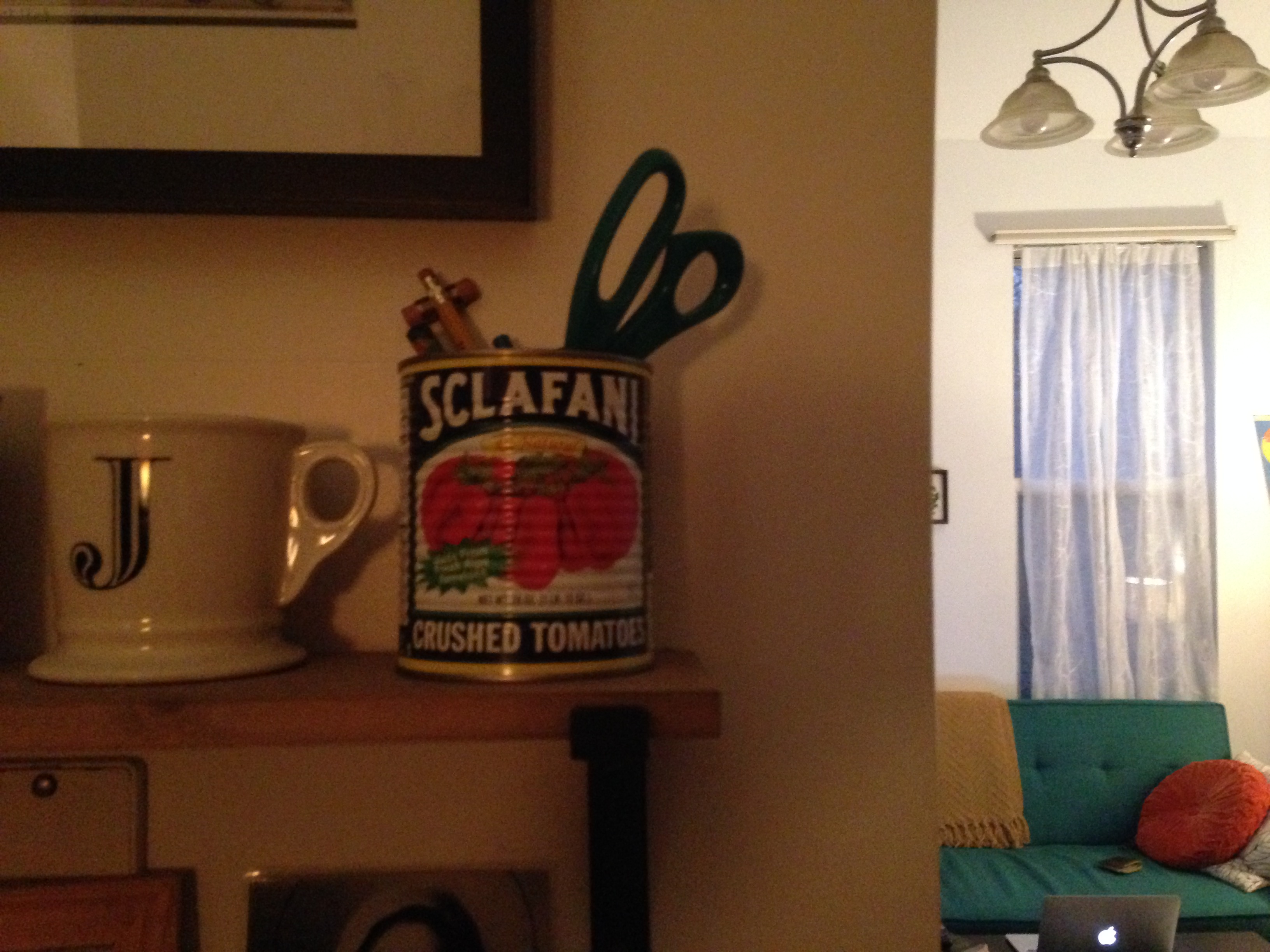 A vintage Sclafani tin can used for scissor and pencil storage in an apartment.