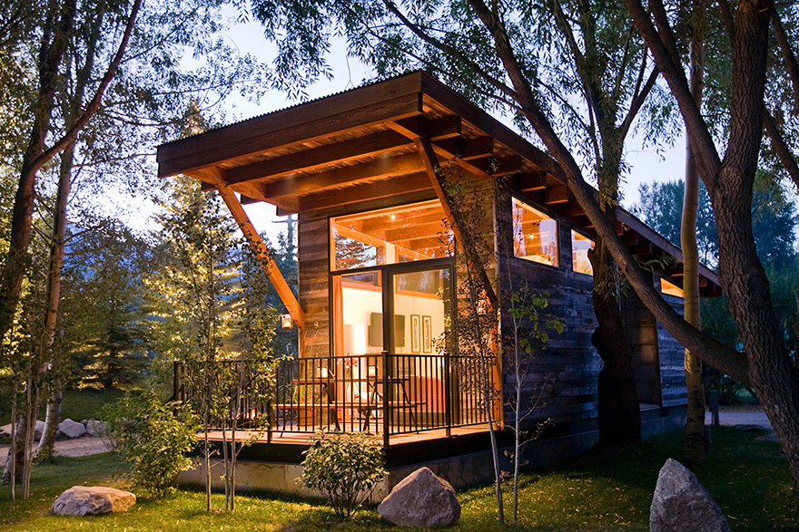 The exterior of a Wheelhaus Wedge cabin in the woods at night.
