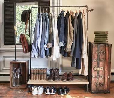 A portable DIY closet made of pipes, a storage crate, a shelf, and a vintage trunk.