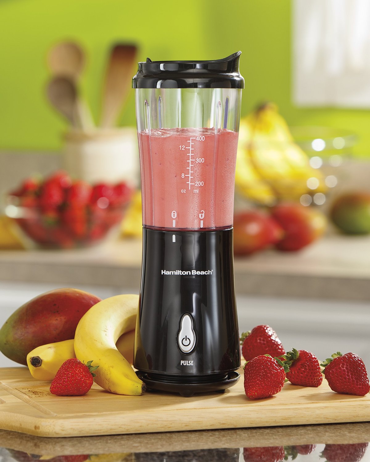A black Hamilton Beach personal blender next to bananas and strawberries on a kitchen counter.