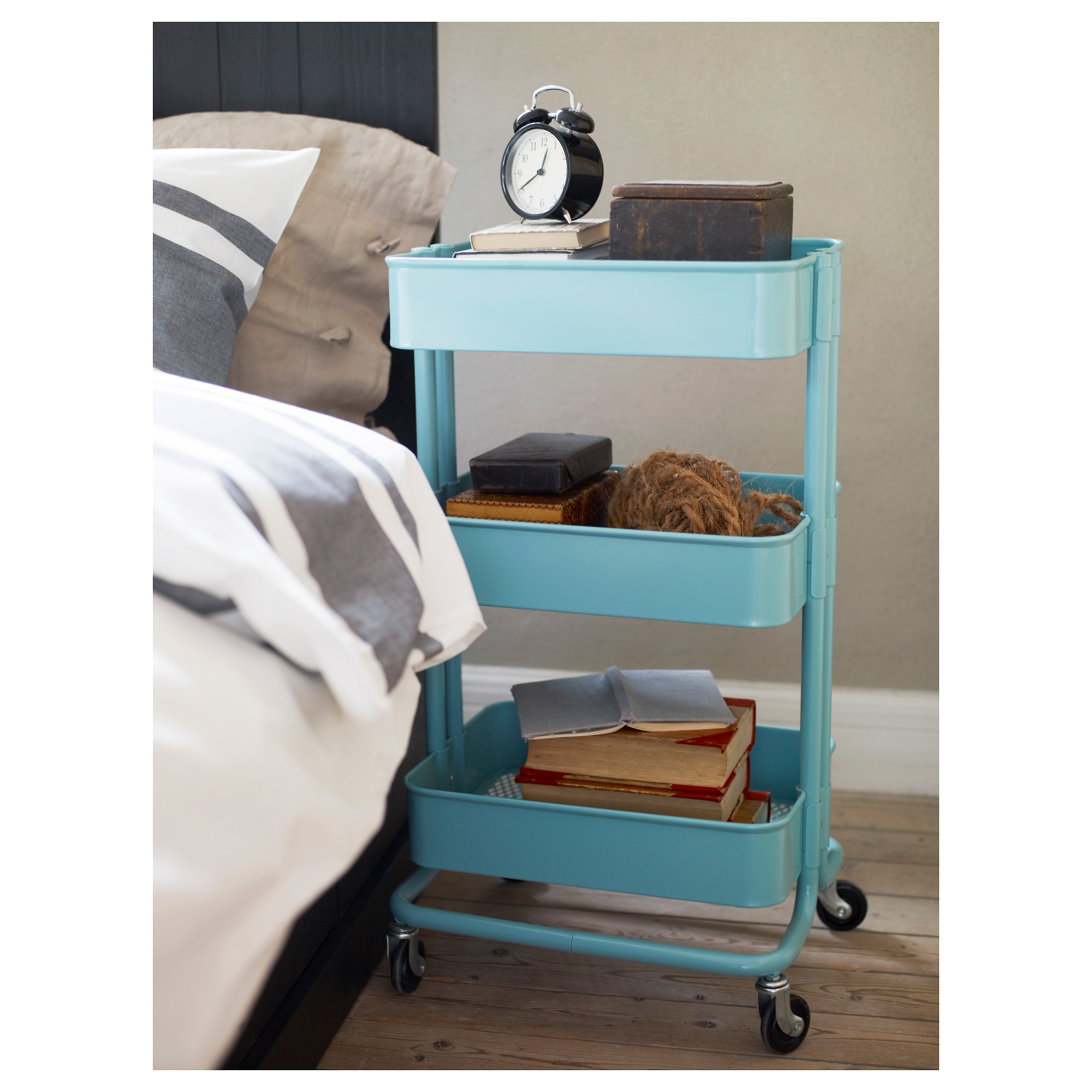 An IKEA Raskog utility cart used as a bedside table.