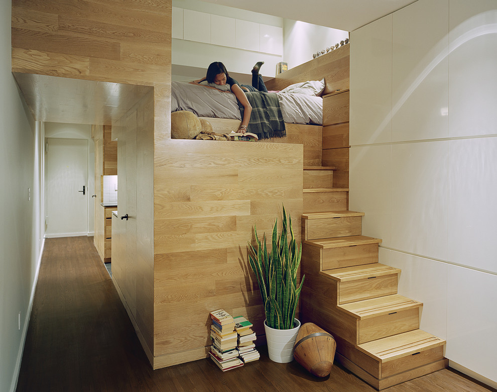 A wooden loft bed in a tiny apartment.