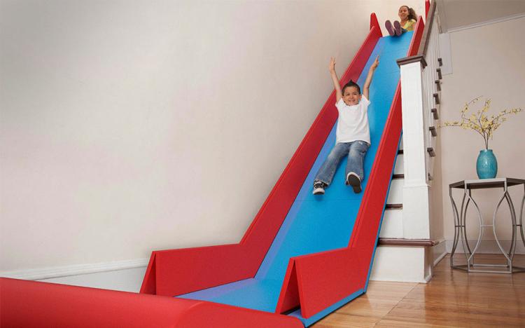 A boy sliding down a Slide Rider, an indoor slide on stairs.