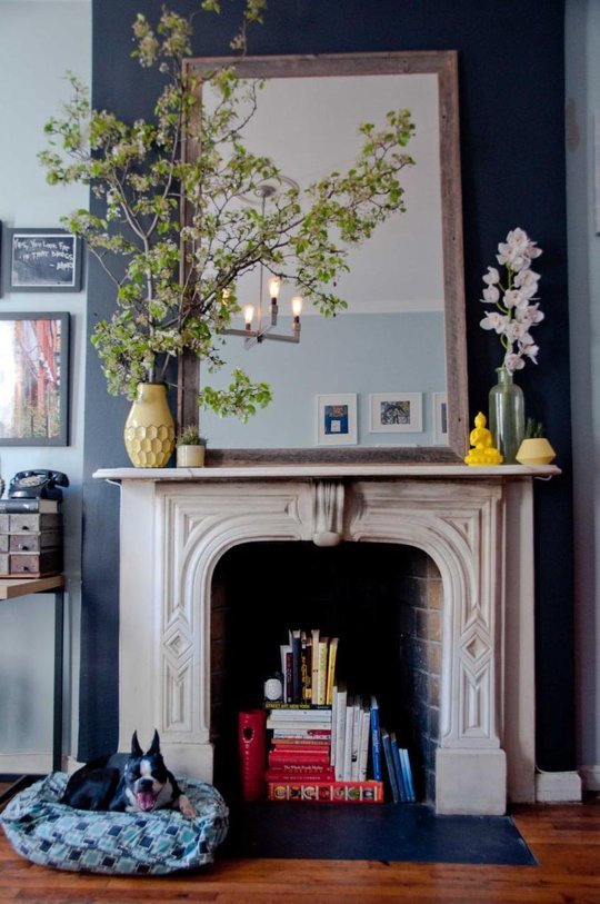 A fireplace used as an easy book storage hack in a 250 sq ft tiny apartment in NYC.
