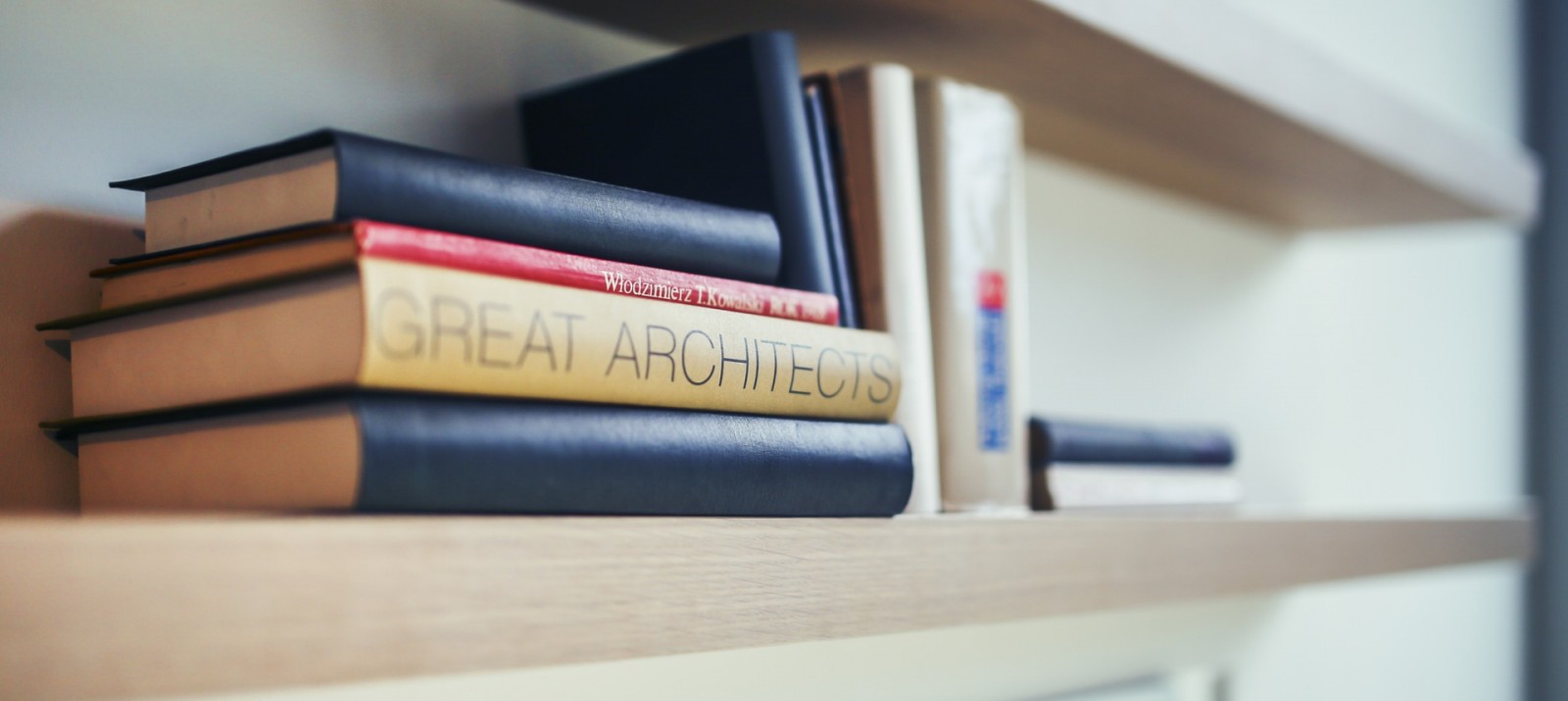 An organized wooden floating bookshelf is storing 11 different books.