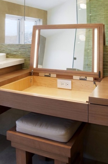 Hidden makeup storage and a mirror with lights is built into a wooden vanity table.