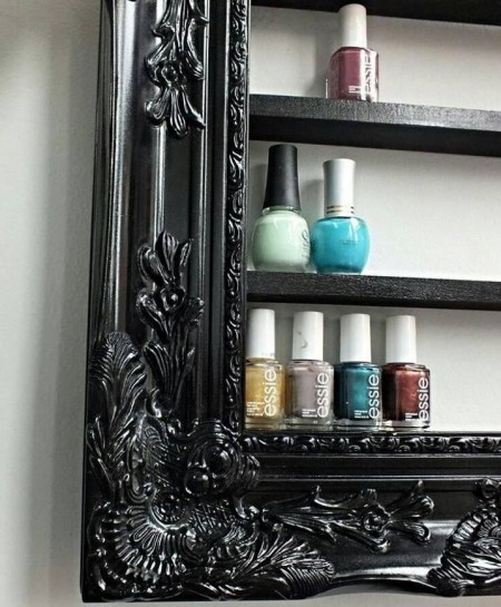 A black DIY picture frame with storage shelves is storing nail polish bottles.