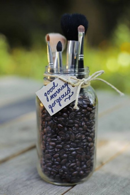 A Mason jar is filled with coffee beans, resulting in a DIY makeup brush holder and air freshener that smells great.
