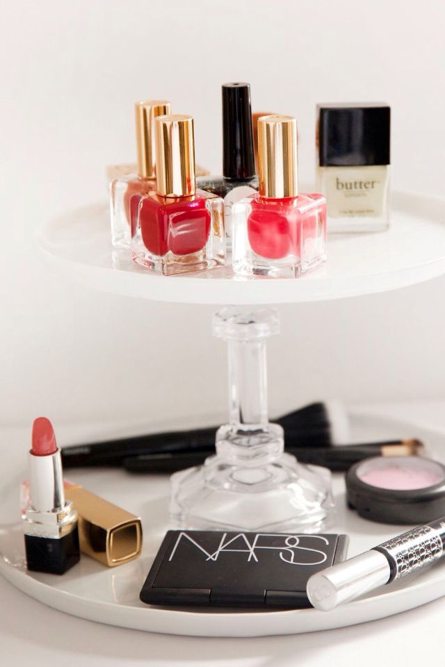 A white tiered cake stand used for fancy and cheap NARS, nail polish, lipstick, and other makeup storage.