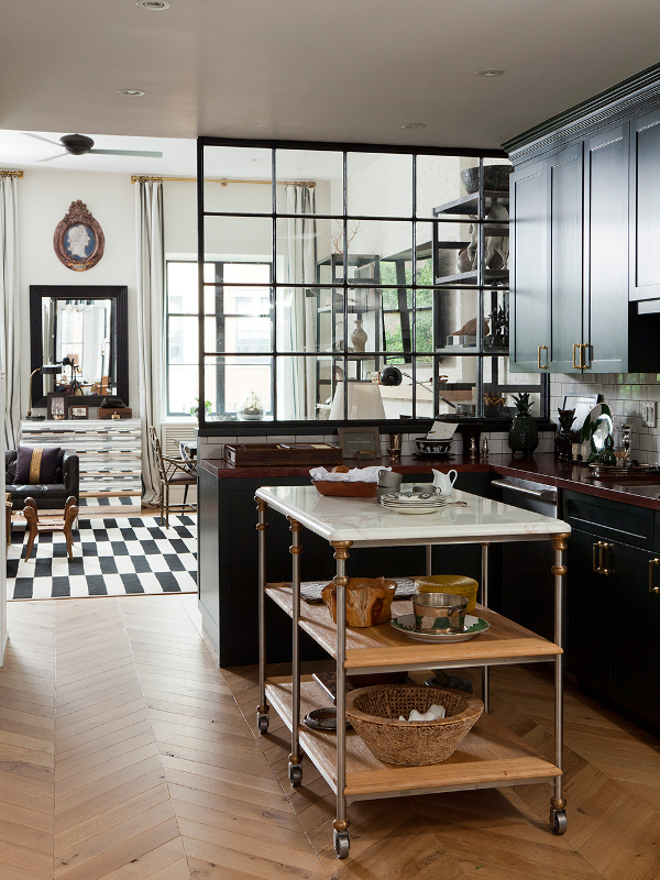 A marble top bar cart is divides a kitchen in a studio apartment.