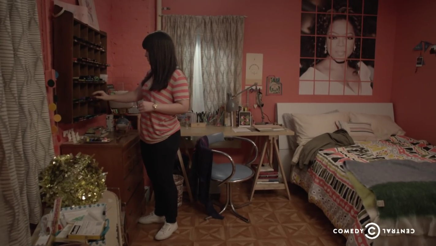 A creative bedroom storage and organizing trick from Broad City: use a multi-purpose desk with storage and a wall-mounted hutch like Abbi does in her Astoria, Queens apartment.