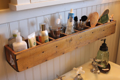 wooden divided box mounted above a sink and storing various bathroom, grooming, and hygiene supplies