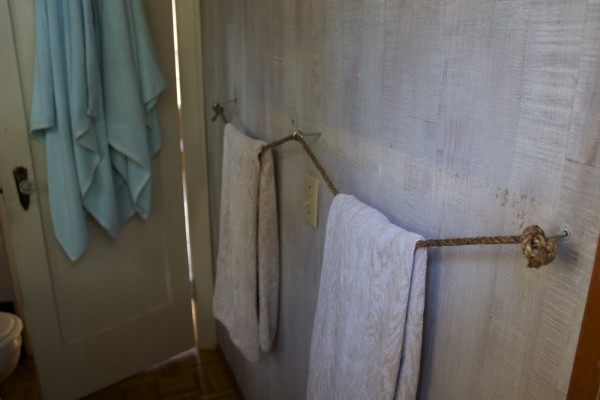 a space-saving bathroom towel rack made from three eye bolts and rope