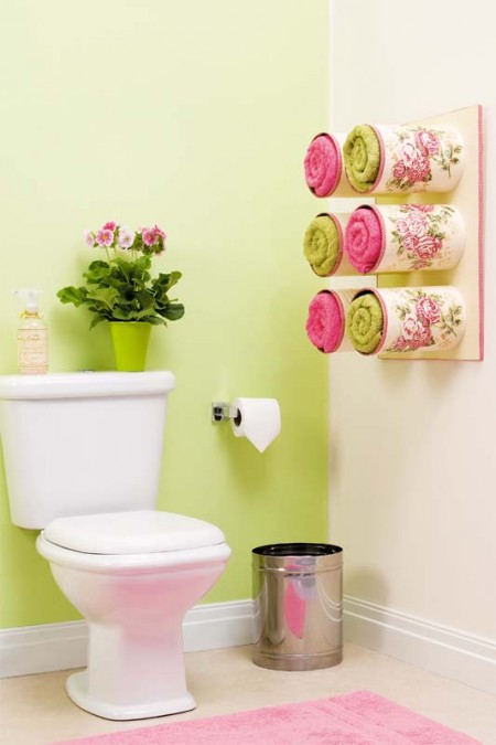 bathroom storage hack: six wall-mounted and decorated tin cans storing six towels