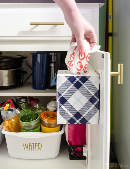 a cabinet door-mounted tissue box is perfect for storing leftover plastic shopping bags