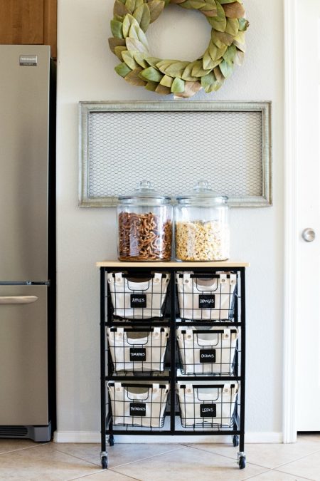 a rolling cart with canvas baskets is an easy way to store snacks and produce in a small kitchen