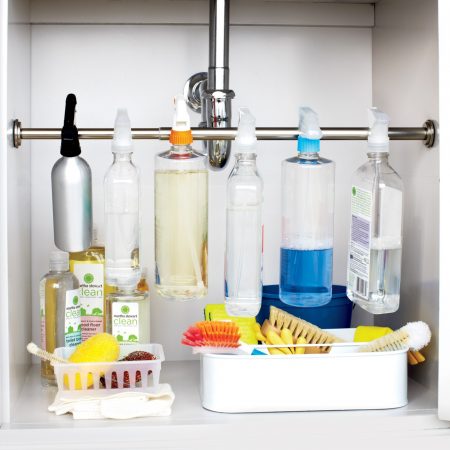 cleaning supplies storage hack: mount a tension rod underneath the kitchen sink